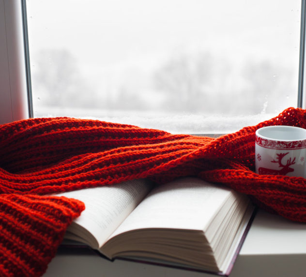 Books, coffee and a scarf on a window sill during a cold winter morning