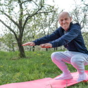 An older man doing squats on an exercise mat