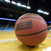 A basketball with NCAA branding rests on a court during a tournament