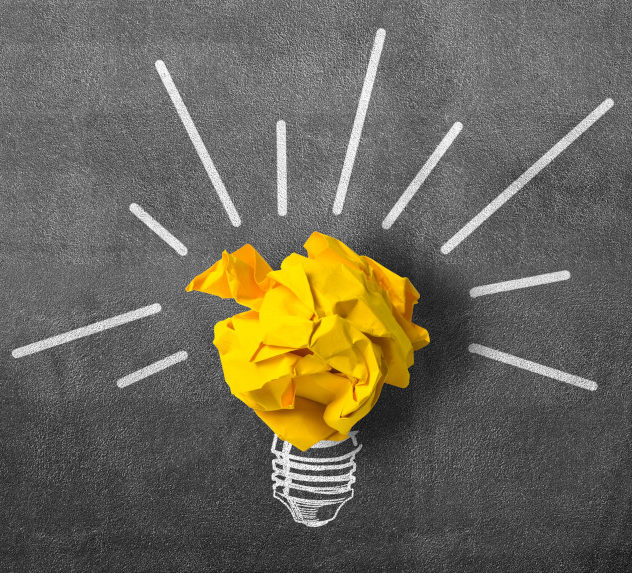 An idea bulb made out of yellow paper curled up into a ball and a chalk drawing for its base.