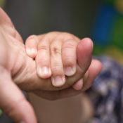 A toddler holding their parent's hand.