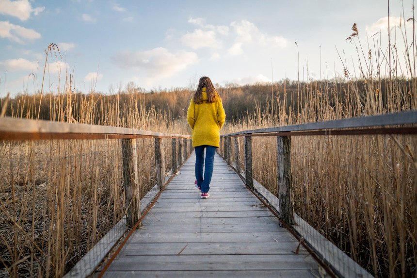 Woman walking on a wooden bridge.