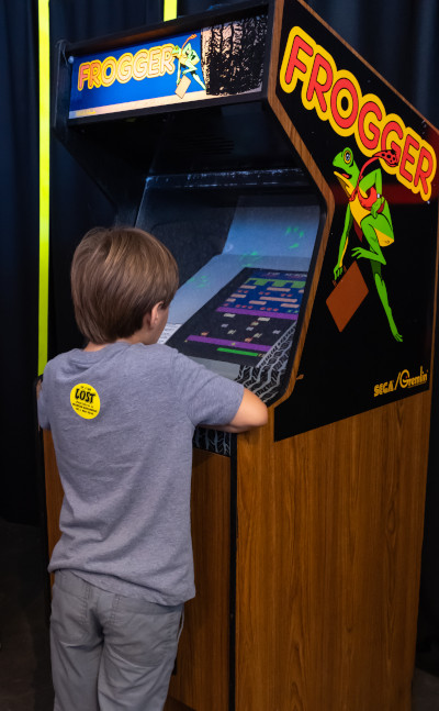 Young boy playing a Frogger arcade cabinet
