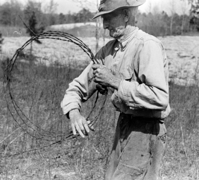 Farmer putting up barbed wire fence.