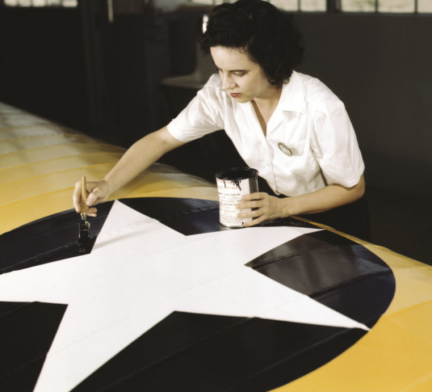 Woman painting the U.S. Army Air Force insignia on an airplane wing.