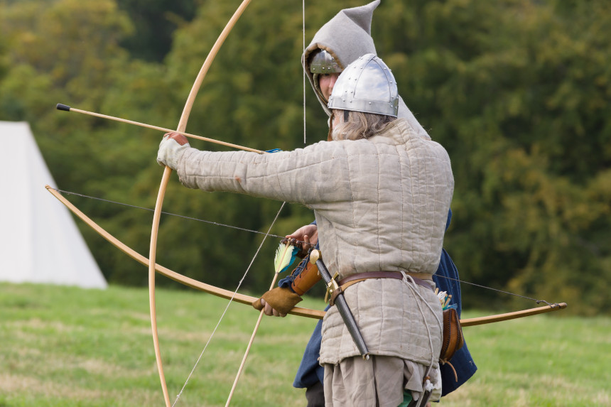 Medieval reenactors prepare to fire a bow.