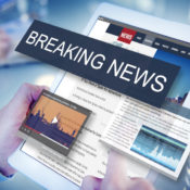 Man holding a tablet with a news website on its screen