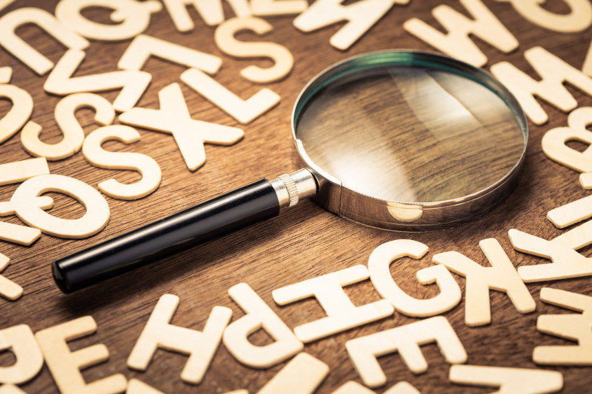 A magnifying glass set in a pile of Latin letters