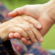 Caregiver holds hand of elderly patient