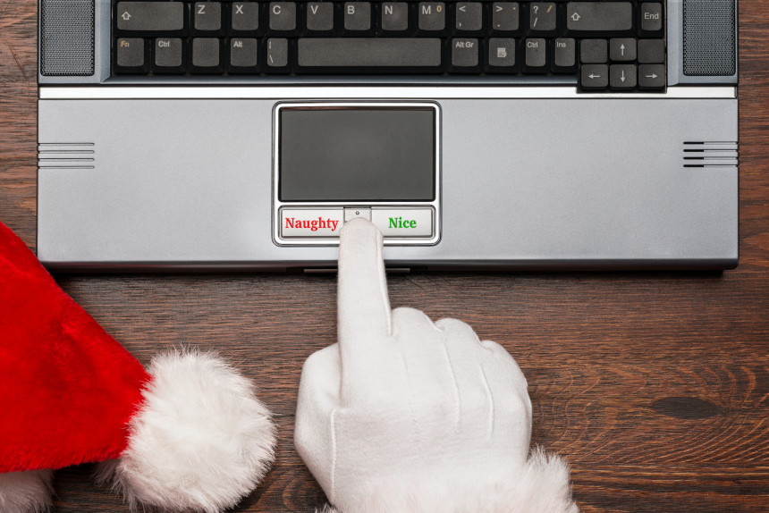 Santa Claus choosing between "Naughty" and "Nice" buttons on a laptop PC