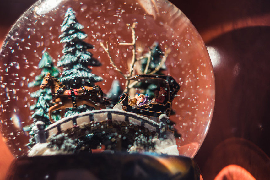 Closeup of a snow globe that displays a family riding a reindeer-drawn sled.