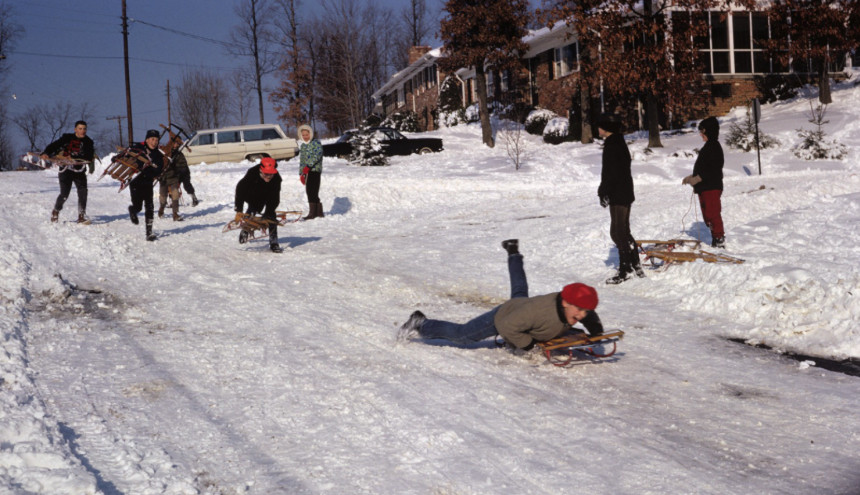 People riding sleds on a snow covered street