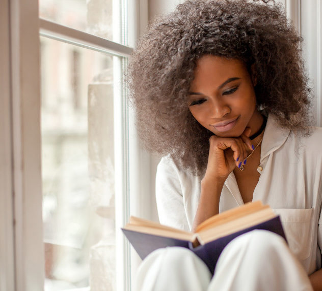 Woman reading a book by her window