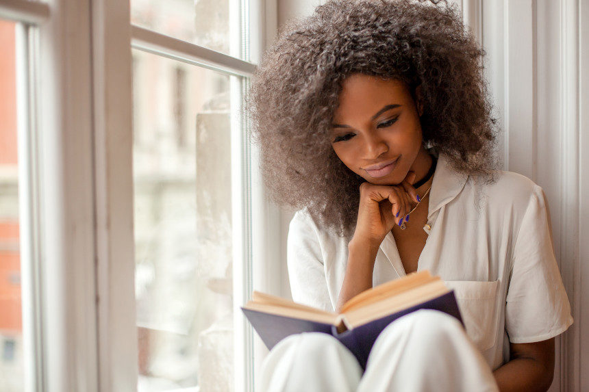 Woman reading a book by her window