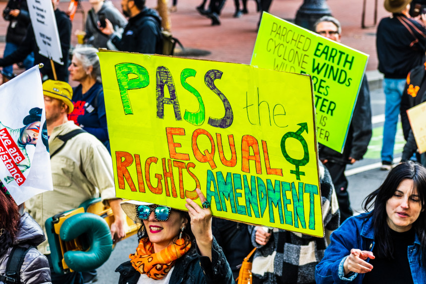 Protestors in a 2022 Women's March hold a sign that reads "Pass the Equal Rights Amendment"