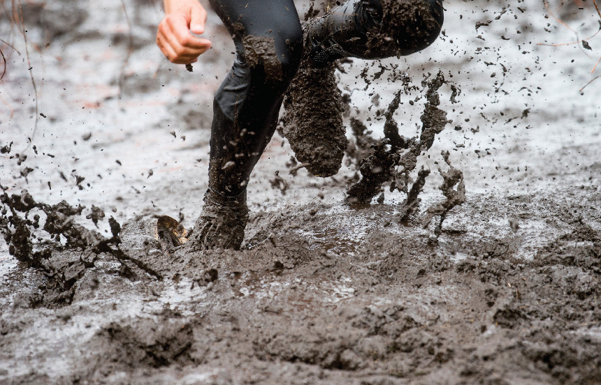 Mud race runner, man running in mud.