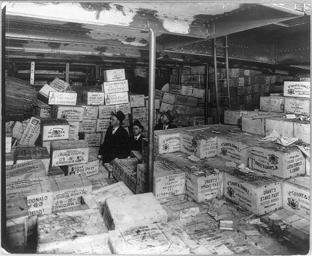 Prohibition agents examining cases of scotch whiskey aboard a rum running ship.