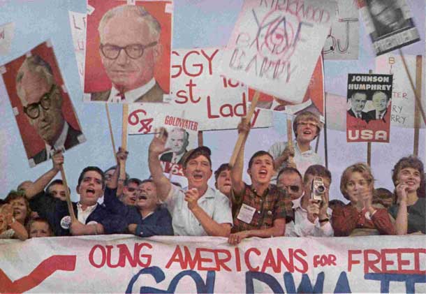 As Goldwaterites welcome their man to St. Louis, rivals Johnson and Humphrey smile calmly from poster held by a Democratic interloper. Photo credit: Burt Glinn The Saturday Evening Post, October 24, 1964.