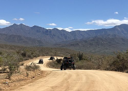 UTVs driving through a desert road.