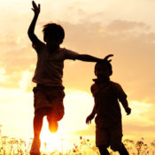 silhouette of three children playing outside in the sunset