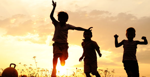 silhouette of three children playing outside in the sunset