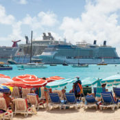 people under umbrellas on sand looking out at cruise ship on the ocean