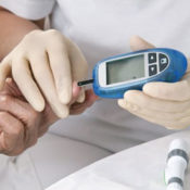 Nurse with latex gloves administering a diabetes blood test