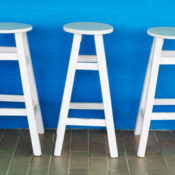 Three white chairs against a blue wall