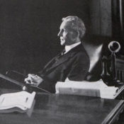 Henry Ford sitting behind a desk and looking out a window, 1913.