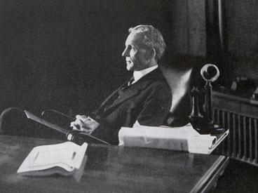 Henry Ford sitting behind a desk and looking out a window, 1913.