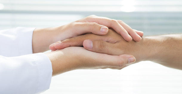 Close-up of doctor and patient holding hands