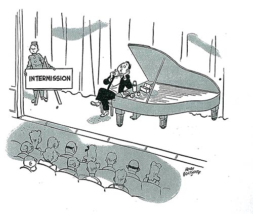 A pianist eats lunch at his grand piano, on stage, as a theatre attendant puts up an "intermission" sign.