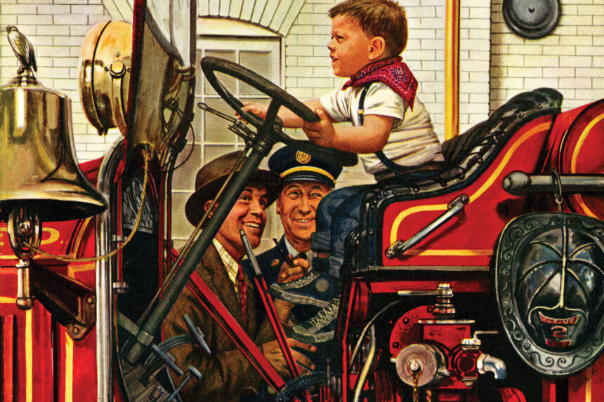 A young boy sits behind the wheel of a firetruck in a firehouse, his face stern as he drives to an imaginary fire, while his father and the fire chief look on and smile.