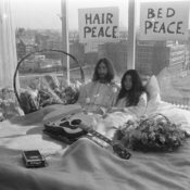 John Lennon and Yoko Onno in a bed with a guitar and flowers.