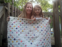 Kym's daughter and granddaughter holding Kym's first quilt.