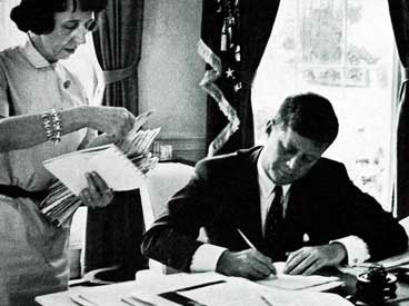 President Kennedy signs documents in the Oval Office. © SEPS 2013