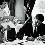 President Kennedy signs documents in the Oval Office. © SEPS