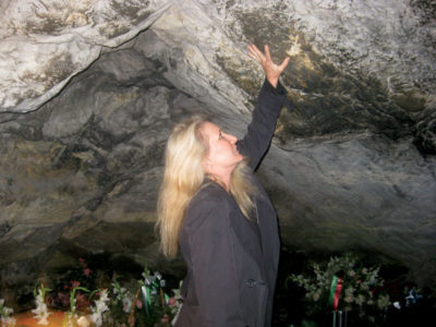 Writer Jill Paris touches the smooth, moist walls of the Grotto of Massabielle, believed to be a source of healing. Photo courtesy Jill Paris.