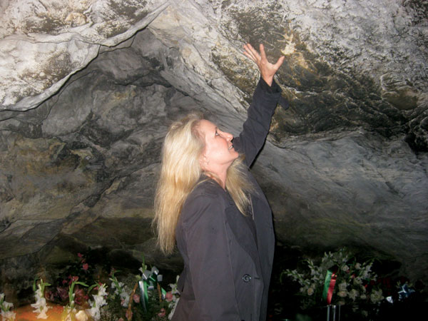 Writer Jill Paris touches the smooth, moist walls of the Grotto of Massabielle, believed to be a source of healing. Photo courtesy Jill Paris.