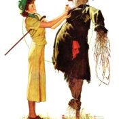 A young woman pins a boutonniere on a scarecrow.