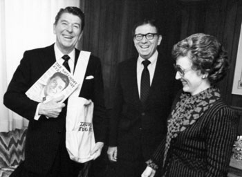Former President Ronald Reagan (left) poses with a copy of The Saturday Evening Post with his portrait on the cover and a Post delivery bag. Dr. SerVaas (center), and Dr. Corey SerVaas (right) look on.
