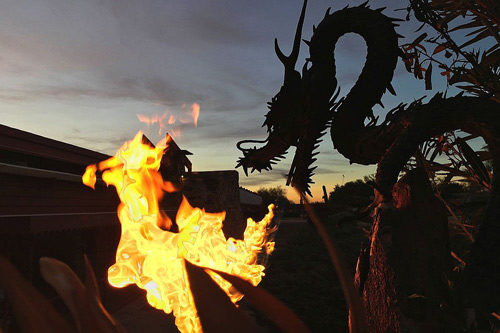 A Chinese dragon next to a blazing firepit.