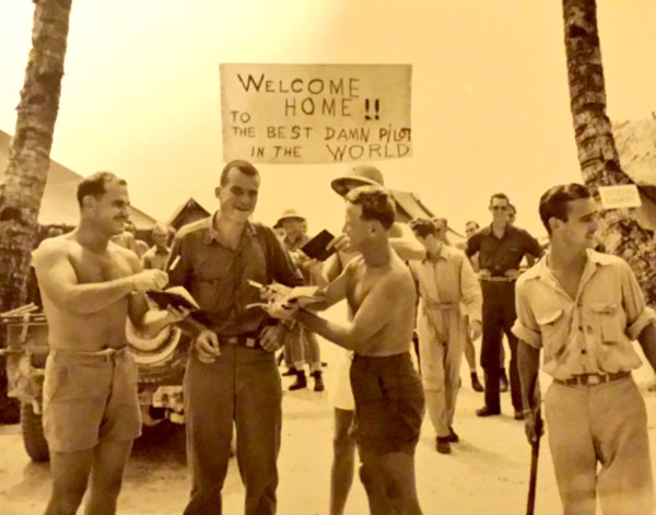 Fellow aviators welcome Lieutenant Guthrie home at base Tarawa, pretending to seek his autograph. 