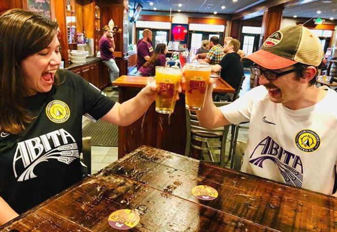 Patrons tapping beer mugs inside Abita