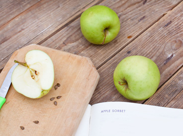 3 apples, cutting board, and cookbook