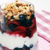 strawberries, blueberries, yogurt, granola in parfait glass