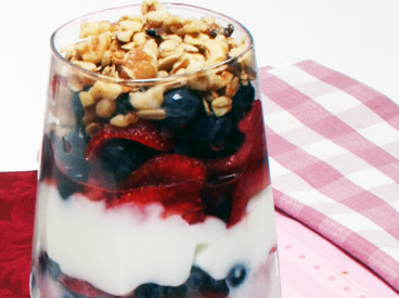 strawberries, blueberries, yogurt, granola in parfait glass