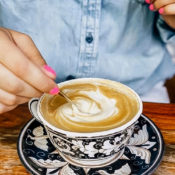 A woman stirs her coffee in a decorative cup.