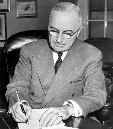 President Harry S. Truman is shown at his desk at the White House signing a proclaimation declaring a national emergency. (National Archives)