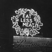 Lit up sign that reads, "Eat Less Meat"